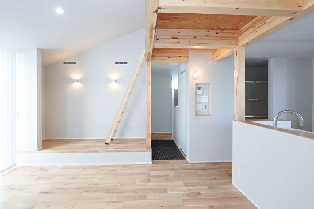 白い壁と無垢材の床が明るい、ナチュラルモダンなリビング空間。小上がりスペースにはロフトへ続く木製のはしごがあり、木の温もりと立体感を感じる間取りです。