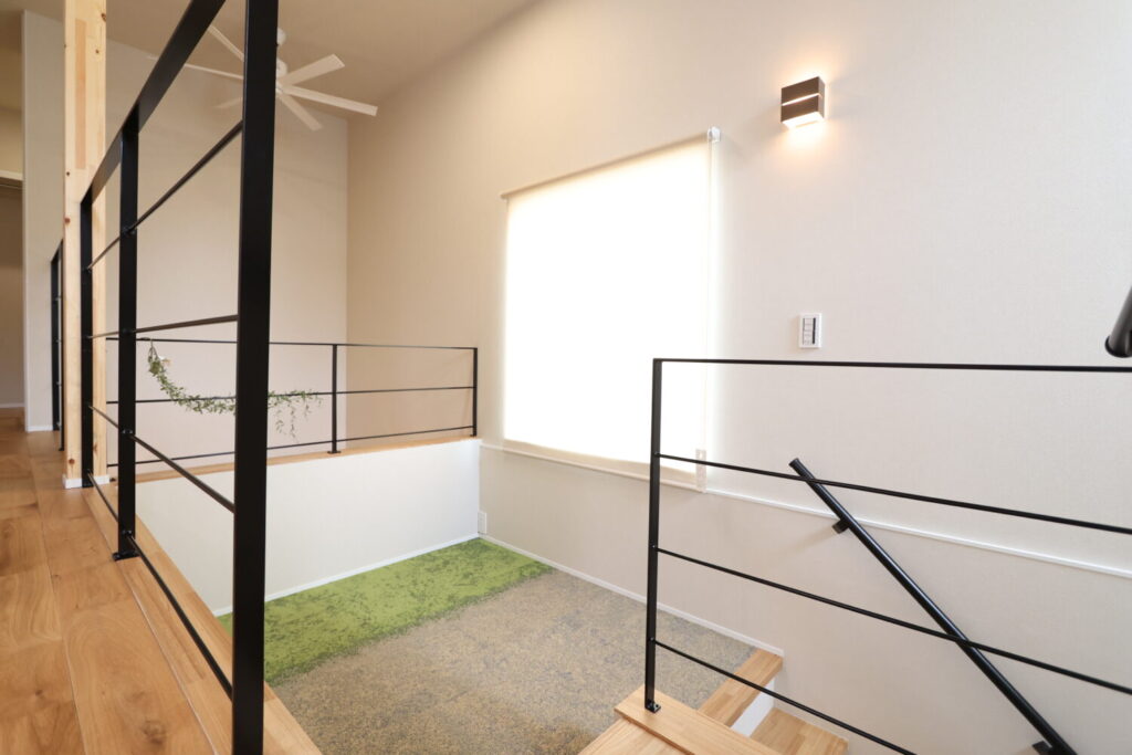 吹き抜けとスキップフロアがつながる、アイアン手すりを採用した明るい新築注文住宅の階段まわり。
